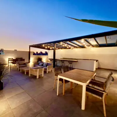 Terraza del roof garden al atardecer con sillones y comedor bajo el pérgolado