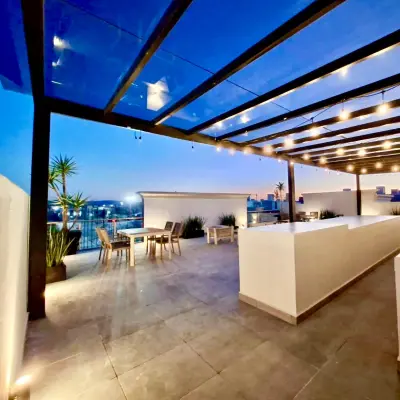 Terraza con barra y comedor, con la ciudad iluminada al fondo