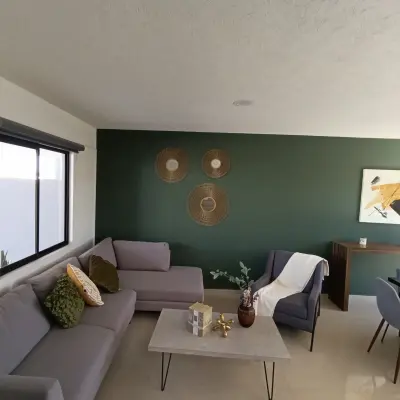 Sala con sofá en L y muro verde de acento